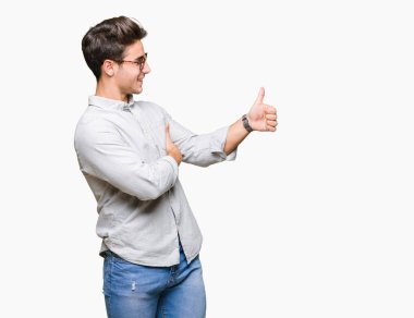 Tarafa jest yapıyor gülümseyen izole arka plan gurur, seyir üzerinde gözlük takan genç yakışıklı adam yaşasın