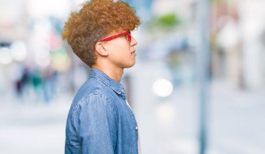 Afro saçlı gözlüklü tarafına, seyir yakışıklı delikanlı dinlenmek doğal yüz emin gülümseme ile pozuyla profili.