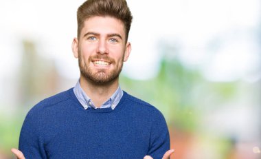 Genç yakışıklı bussines başarı işareti başparmak gülümseyen ve mutlu el ile pozitif jest yapıyor adamım. Neşeli bir ifadeyle, kazanan jest kameraya bakıyor.