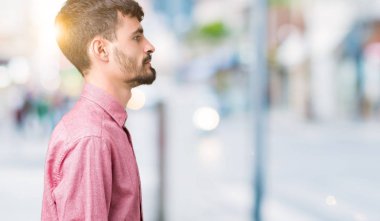 İzole arka tarafına, seyir üzerinde pembe gömlek giymiş genç yakışıklı adam sakin ol kendine güvenen gülümseme ile doğal yüz pozuyla profili.