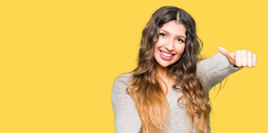 Genç güzel kadın el ile olumlu jest yapıyor onaylamak kış elbise giyen, gülümseyen ve başarı için mutlu kadar başparmak. Kamera bakarak, kazanan jest.