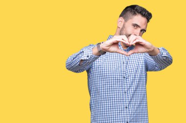 Yakışıklı delikanlı aşık kalp simgesi ve elleriyle şekil gösteren gülümseyen izole arka plan üzerinde. Romantik kavramı.