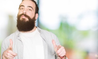 Uzun saç, sakal ve fotoğraf makinesi ile mutlu ve komik yüz için parmakları işaret küpe olan genç adam. İyi enerji ve vibes.