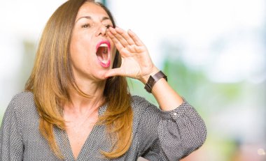 Bağırarak ve ağzı üzerinde el ile yan için çığlık güzel orta yaş iş kadını. İletişim kavramı.