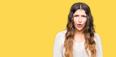 Korkuyor ve şok sürpriz ifade, korku ve heyecan yüz beyaz kazak giyen genç güzel kadın.