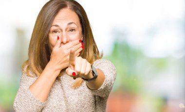 Moda kazak giyen güzel orta yaş kadın gülme sizin parmak el kamerasıyla ağzına, utanç ifadesi işaret eden