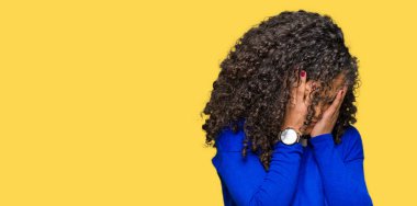 Genç güzel kadın kıvırcık saçlı yüz eller ile ağlayarak süre kapsayan üzgün ifade ile kış kazak giyiyor. Depresyon kavramı.