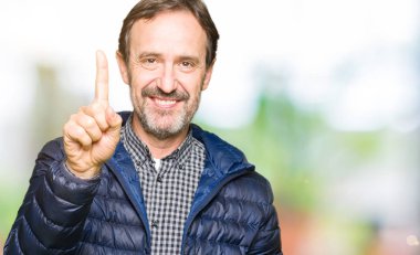 Orta yaş yakışıklı adam kış ceket gösteren giyen ve kendinden emin ve mutlu gülümserken parmak bir numara ile işaret.