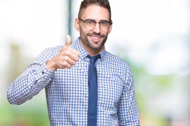 İzole arka planda gözlük takan genç iş adamı el ile jest kadar mutlu başparmak yapıyor. Başarı gösteren kameraya bakarak ifadeyi onaylama.