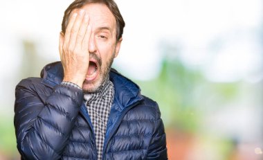 Orta yaş yakışıklı adam kış ceket giyen Yaslama yorgun yarım yüz, göz ve ağız el ile kapsayan. Yüz acı içinde acıyor.