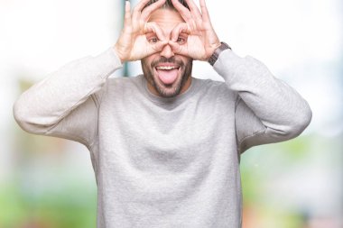 Dilini, parmaklarının arasından baktığını yapışmasını dürbün gibi ok jest yapıyor izole arka plan üzerinde sweatshirt giyen genç yakışıklı adam. Deli ifade.