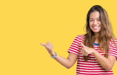 Giyen genç güzel esmer kadın çizgili tişört izole arka plan üzerinde emin gülümseyen arkasından el ve kadar başparmak ile işaret