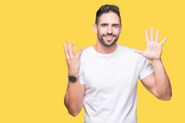 Gösterilen ve parmakları ile işaret izole arka plan üzerinde rahat beyaz t-shirt giyen genç adam numara 9 kendinden emin ve mutlu gülümseyerek süre.