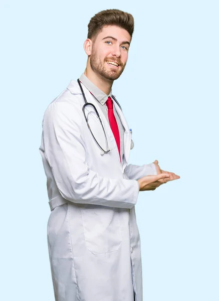 Młody Przystojny Lekarz Mężczyzna Noszenie Płaszcz Medyczny Zapraszając Wejścia Uśmiechnięty — Zdjęcie stockowe