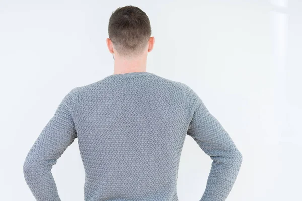 カジュアルなセーターを着た若いハンサムな男は 体に腕を持って後ろ向きに立って 孤立した背景の上にカジュアルなセーターを着て — ストック写真