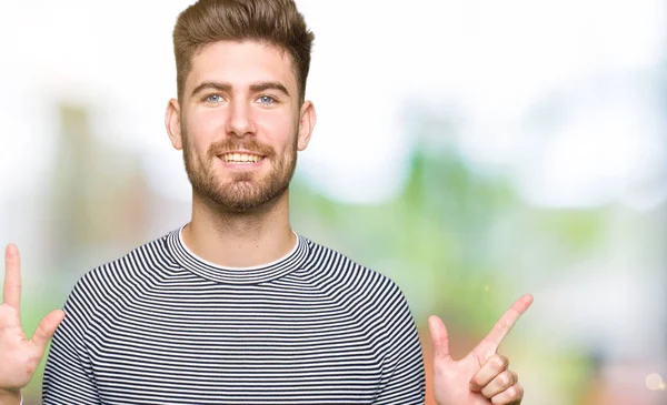 ストライプ セーター表示と指で上向きを身に着けている若いハンサムな男性数は自信を持って 幸せな笑みを浮かべている間 — ストック写真