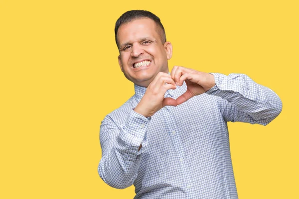 Middle age arab business man over isolated background smiling in love showing heart symbol and shape with hands. Romantic concept.