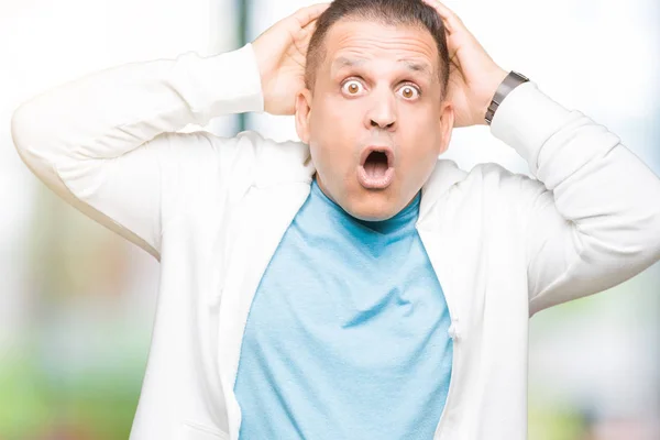 Middle age arab man wearing sweatshirt over isolated background Crazy and scared with hands on head, afraid and surprised of shock with open mouth