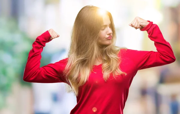 若い美しい金髪女性の誇りに思って笑顔腕の筋肉を示す孤立した背景に赤いセーターを着ています フィットネスの概念 — ストック写真