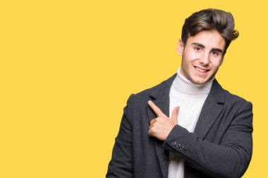 Zarif delikanlı izole arka neşeli bir gülümseme ile yüz el ve parmak kadar mutlu ve doğal ifade yüzünde yanında işaret içinde kış palto giyiyor