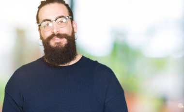 Genç hipster adam uzun saçlı ve gözlüklü eller birlikte sakal ve parmakları ile rahat ve neşeli gülümseyen geçti. Başarı ve iyimser