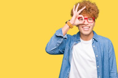 Yakışıklı delikanlı afro saçlı gözlüklü gülümseyen, parmakları ile mutlu yüz üzerinden seyir göz el ile ok jest yapıyor.