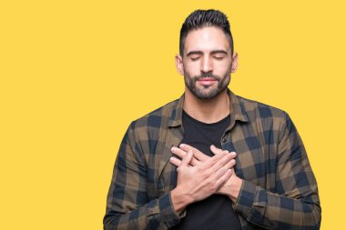 Yakışıklı delikanlı ile gülümseyen izole arka plan üzerinde kapalı gözler ve yüzünde minnettar jest ile göğüs üzerinde eller. Sağlık kavramı.