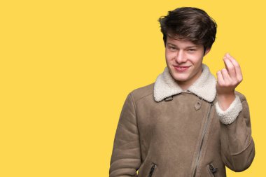 İzole arka plan üzerinde kış ceket giyen genç yakışıklı adam el ve parmaklar emin ifade ile Italyan jest yapıyor