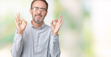 Orta yaş zarif komuta sizde gözlük izole arka plan üzerinde dinlenmek ve parmak ile meditasyon jest yapıyor kapalı gözlerle gülümseyen yakışıklı. Yoga kavramı.