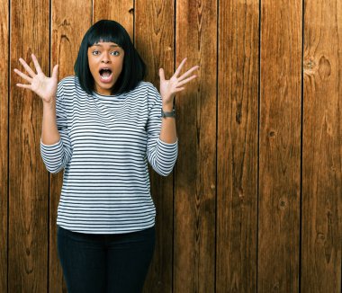 Güzel genç Afrikalı Amerikalı kadın izole arka plan üzerinde çizgili kazak giyiyor deli kutluyor ve başarı için hayran silah kaldırdı ve açık gözleri heyecanlı çığlık. Kazanan kavramı