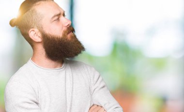 Silah ile yan bakarak gülümseyen rahat kazak giyen genç sarışın adam ikna ve emin geçti