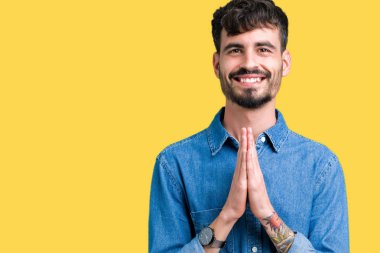 Yakışıklı delikanlı birlikte emin gülümseyen bağışlanmak ellerle dua izole arka plan üzerinde.
