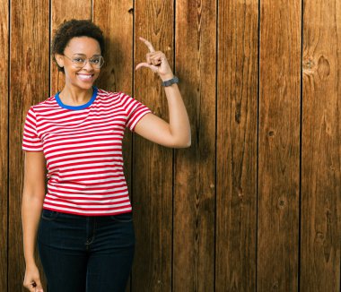 Güzel genç Afro-Amerikan kadın gözlük gülümseyen izole arka plan ve süre seyir ve kamera boyutu işaret parmaklarıyla yapıyor el ile kendinden emin eller üzerinde. Ölçü kavramı.