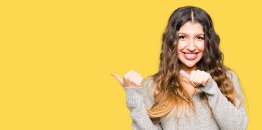 Genç güzel kadın giyiyor kış giysi işaretleme için arkasından el ve başparmak ile kendinden emin gülümseyen