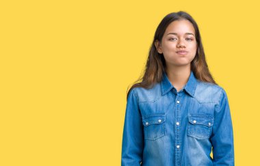 Komik surat ile yanakları şişirme izole arka plan üzerinde mavi kot gömlek giyen genç güzel esmer kadın. Ağız ile hava, deli ifade şişirilmiş.