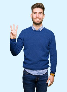 Gösterilen ve parmakları ile işaret genç yakışıklı bussines adam kendinden emin ve mutlu gülümseyerek iken üçüncü.