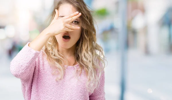 美丽的年轻金发碧眼的女人在孤立的背景偷看在震惊覆盖的脸和眼睛用手 通过手指寻找尴尬的表情 — 图库照片