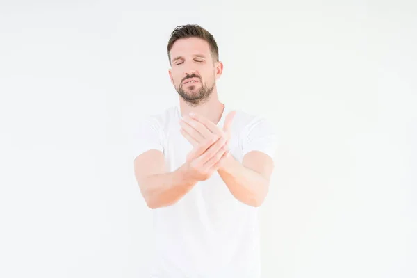 年轻英俊的男人穿着休闲白色 T恤在孤立的背景下遭受疼痛的手和手指 关节炎炎症 — 图库照片