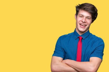 İzole arka plan üzerinde kırmızı kravat giyen genç yakışıklı iş adamı kamera bakarak çapraz silah ile gülümseyen yüz. Pozitif kişi.