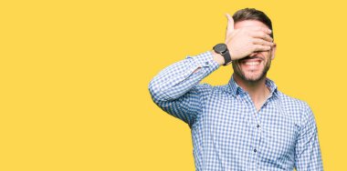 Gülümsüyor ve gözleri için sürpriz kapsayan yüz el ile gülüyor mavi gözlü yakışıklı iş adamı. Kör kavramı.