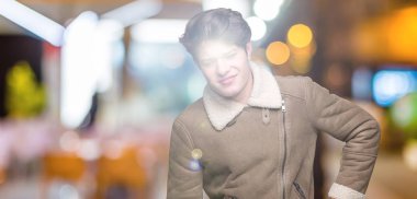 Genç yakışıklı adam giyen kış ceket izole üzerinde arka plan geri el ile kas ağrısı dokunmadan acı sırt ağrısı,