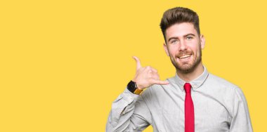 Genç yakışıklı iş adamı yapıyor gülümseyen telefon hareketi ile el ve parmak telefonda konuşuyor gibi. Kavramları iletişim.