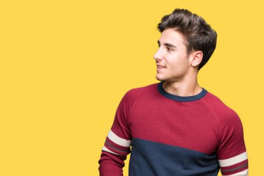 Yakışıklı delikanlı uzak tarafına yüzünde, doğal ifade gülümseme ile seyir izole arka plan üzerinde. Kendine güvenen gülüyor.