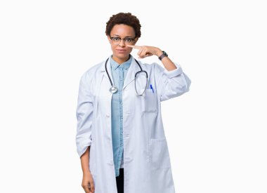 Tıbbi kat izole üzerinde giyen genç Afro-Amerikan doktor kadın arka plan işaretçi el parmak yüz ve burun, neşeli gülümseyen
