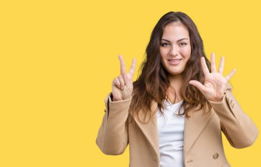 Parmakları ile 7 ise kendinden emin ve mutlu gülümseyen güzel artı boyutu genç kadın giyiyor kış ceket ve yukarıyı gösteren izole arka plan üzerinde numara.