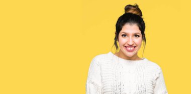 Yüzünde mutlu ve havalı bir gülümseme olan kışlık süveter giyen genç ve güzel bir kadın. şanslı kişi.