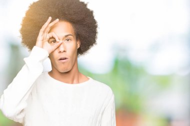 Sürpriz yüz, göz parmaklarının arasından seyir ile ok jest yapıyor kış kazak giyen afro saçlı genç Afro-Amerikan adam şok. İmansız ifade.