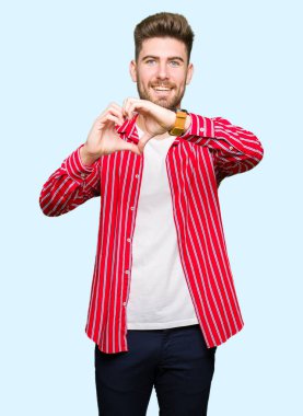 Kırmızı gömlek aşık kalp simgesi ve elleriyle şekil gösteren gülümseyen yakışıklı delikanlı. Romantik kavramı.