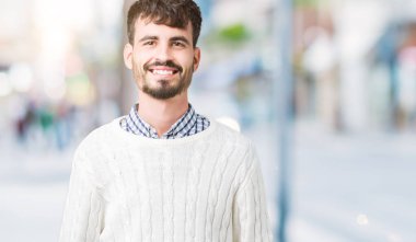 Yüzünde mutlu ve güzel bir gülümseme ile izole arka plan üzerinde kış kazak giyen genç yakışıklı adam. Şanslı kişi.