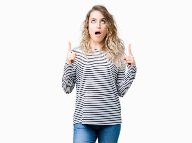 İzole arka plan üzerinde çizgili süveter giyen güzel genç sarışın kadın hayrete ve yukarıya bakıyor ve parmakları ile işaret ve silah kaldırdı şaşırttı.